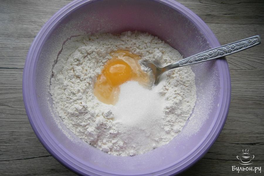 В муку добавить куриное сырое яйцо, щепотку мелкой соли, сахарный песок и соду.
